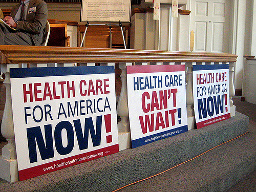 Posters saying "Health Care for American Now!" and "Health Care Can't Wait!"